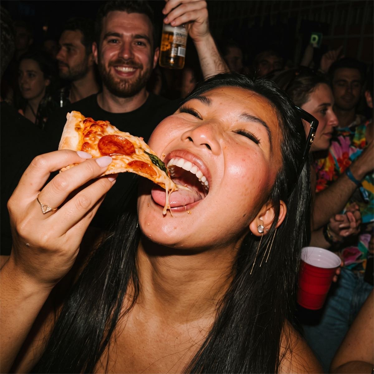 Ein Gast lacht und isst ein Stück Pizza mitten auf dem Fest.